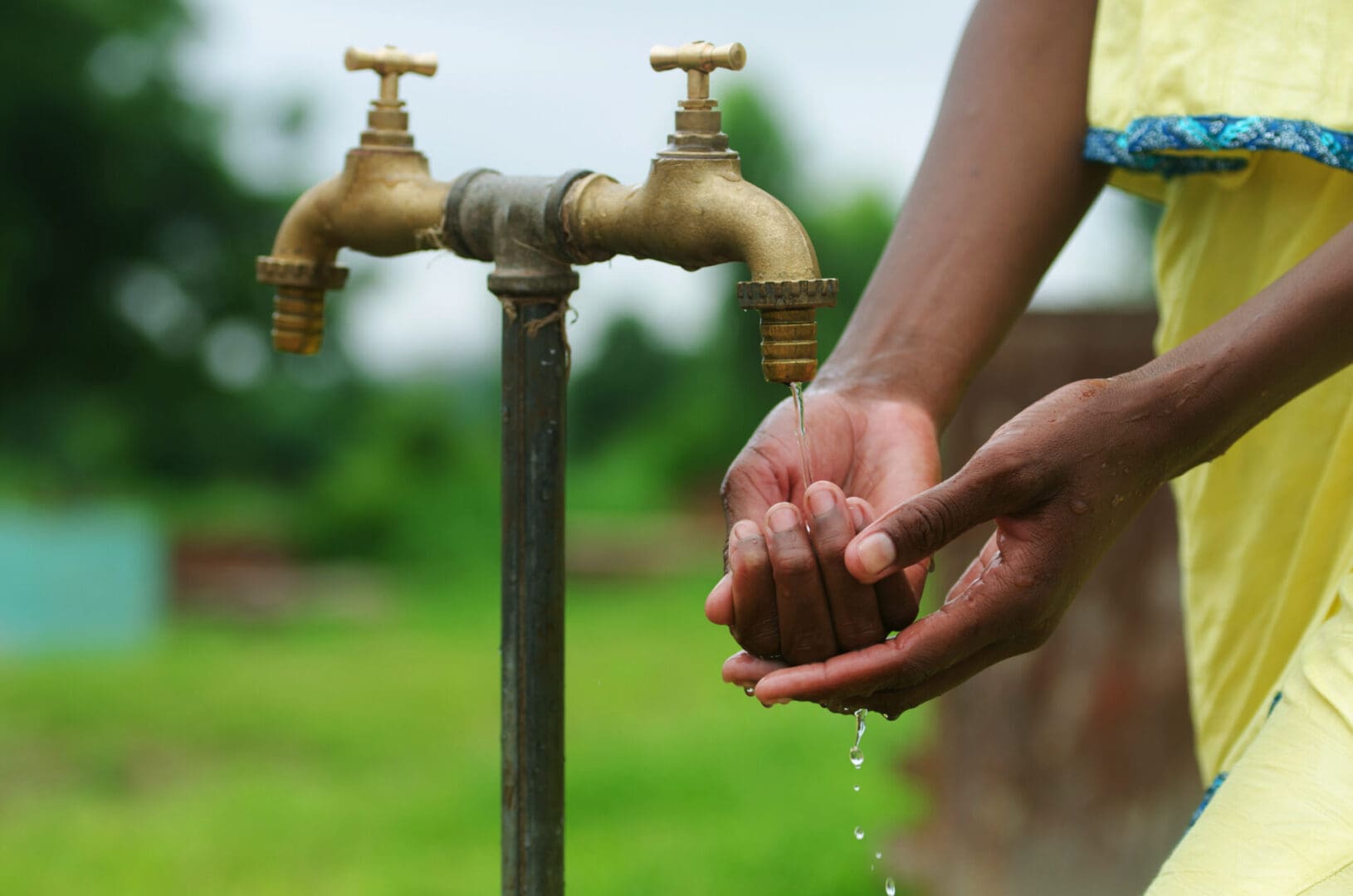 Beautiful shot of African girl holding hand under water tap in Bamako, Mali as a water for health concept. Environment, peace, freedom, life. This is what matters for African women now.